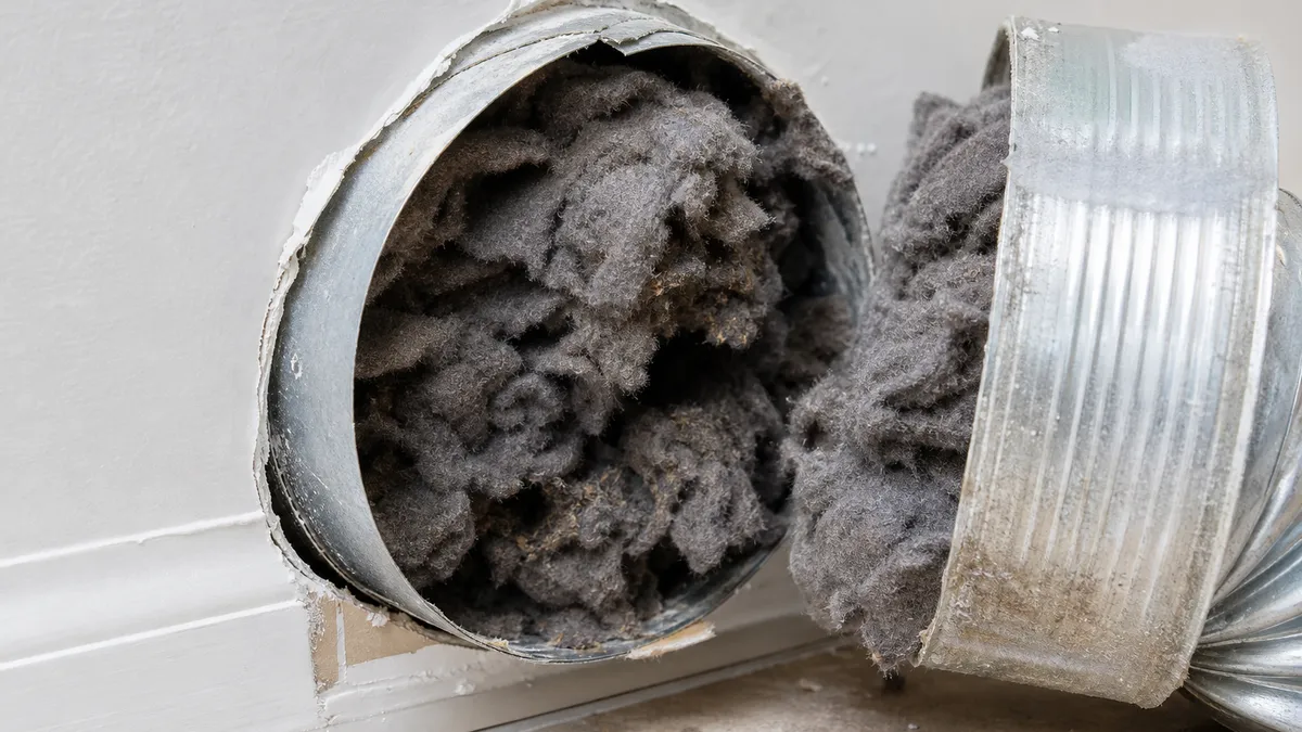 Clogged dryer vent duct packed with lint exposed during inspection, a fire hazard